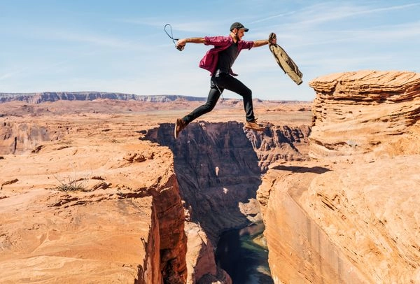Man Jumping Across a Canyon Gap, Symbolizing Bridging the Gap in Diversity, Equity & Inclusion Efforts