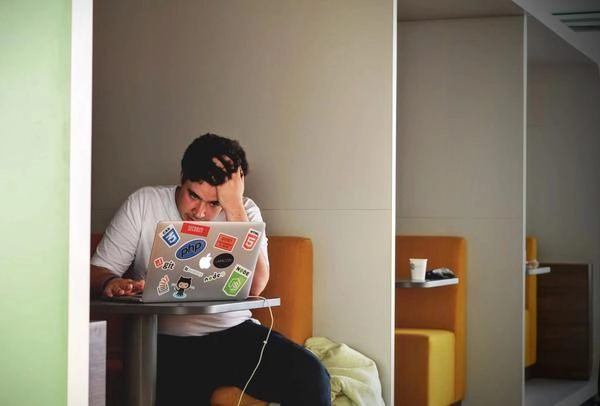 Millennial worker pulling his hair in front of laptop from being stressed