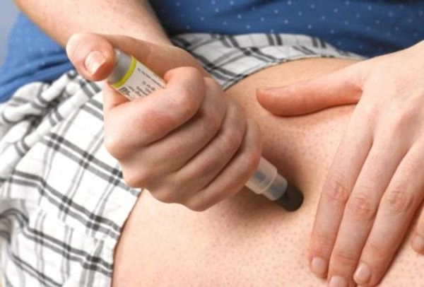Boy injecting his thigh with epipen due to allergic reaction.