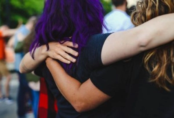 A Group of Employees Hugging Outside, Viewed from Behind. One of them has Purple Hair.