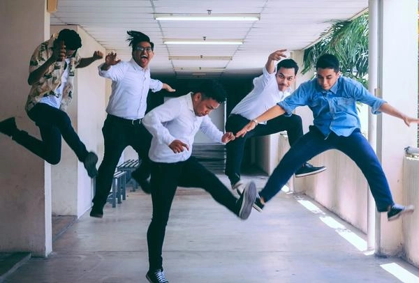 Five employees jumping from excitement in an office hallway