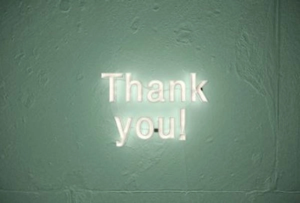 White neon sign on green wall reading "Thank you!"