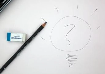 Question mark drawn on a white piece of paper beside a pencil and eraser