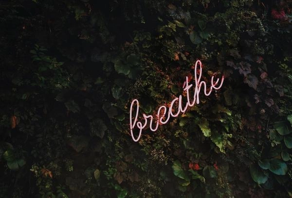 Neon sign reading "breathe" to represent employees dealing with stress.