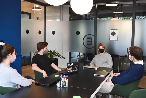 Four team members wearing a mask in a conference room at work